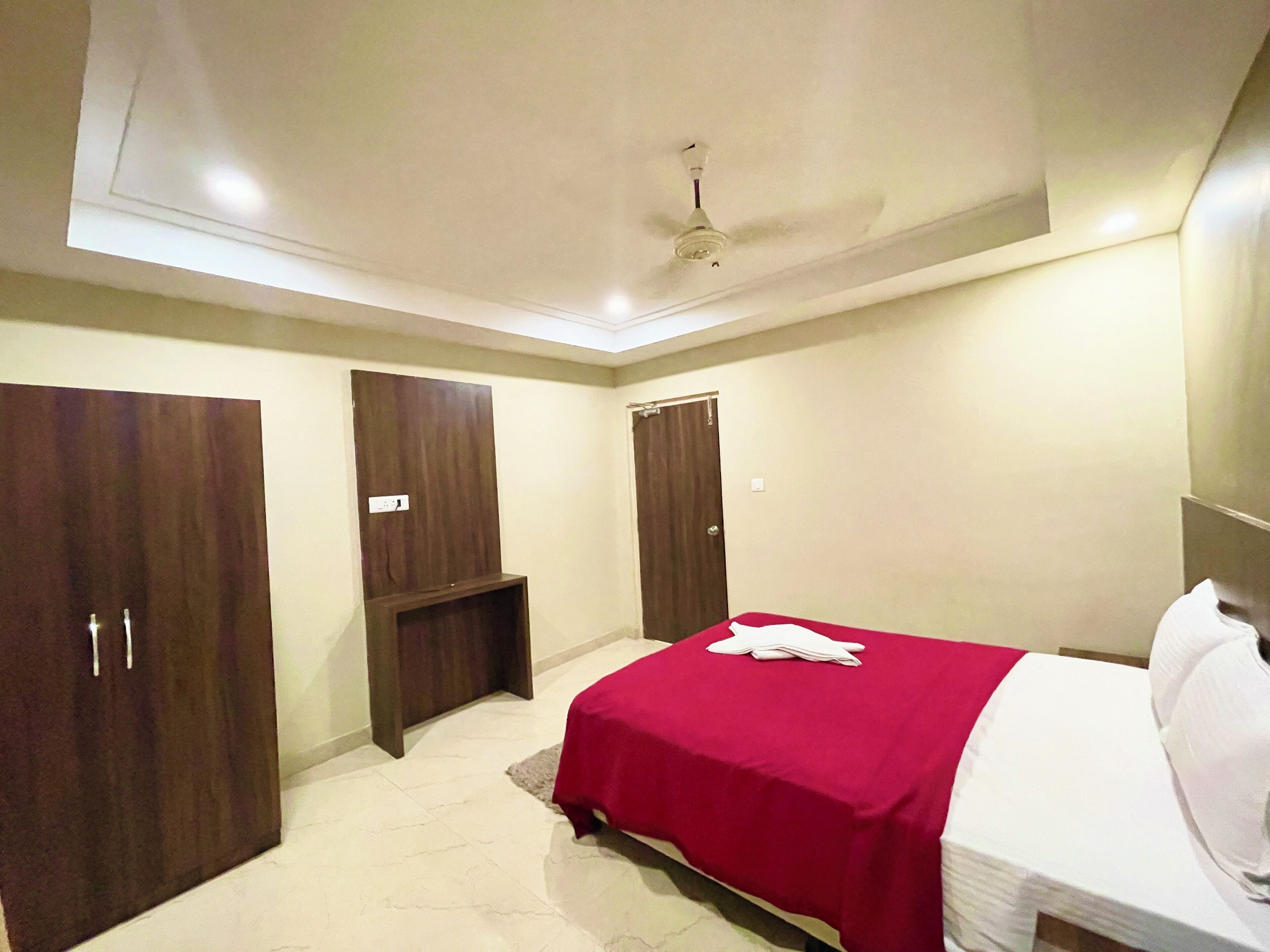 A bedroom with a bed, a ceiling fan, and two wardrobes.