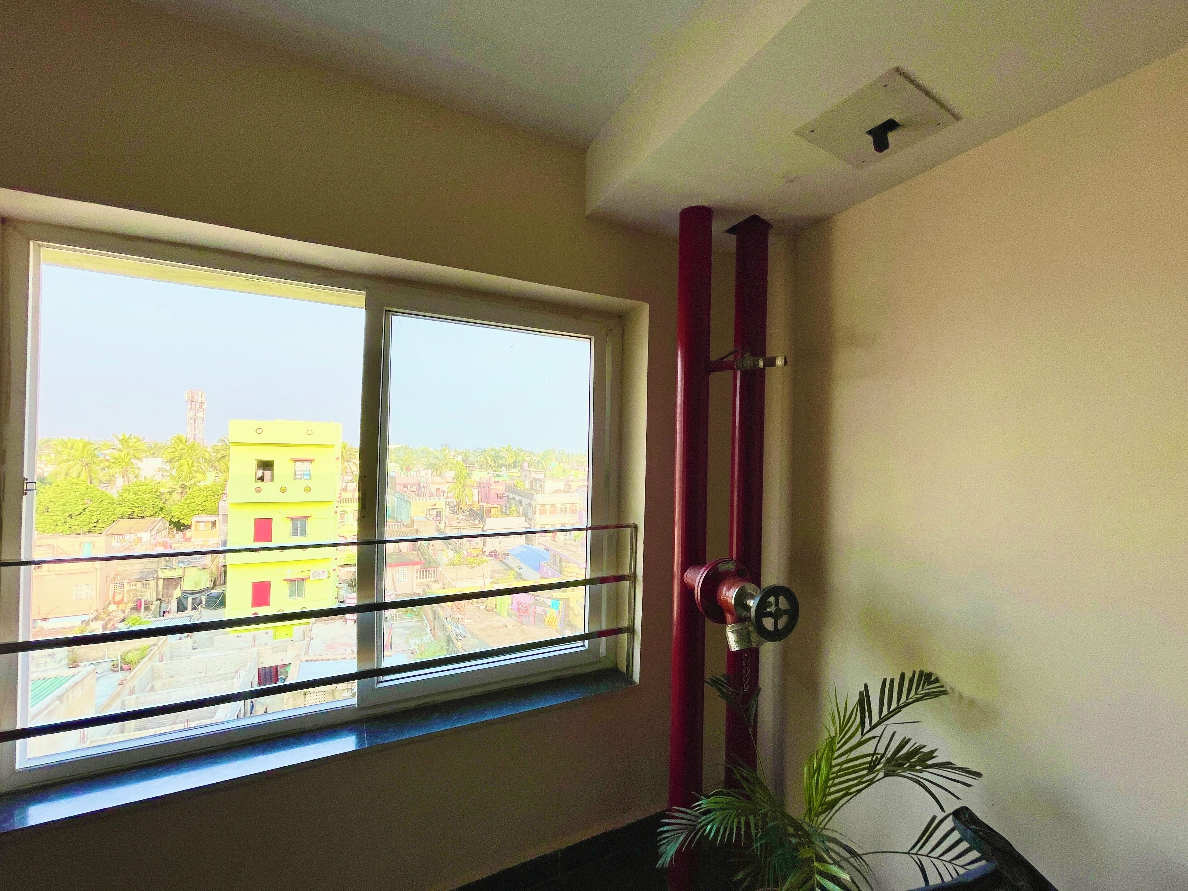 A room with a large window offering a view of a residential area.