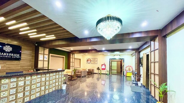 A hotel lobby with a reception desk, seating area, and a chandelier. - Hotel Janaki Pride - near Temple (Puri)