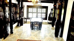A room with a marble floor, a central table with chairs, and a large window with bars. - Heritage Villa (Mangaluru)