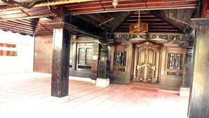 A traditional wooden building with a large ornate door and columns. - Heritage Villa (Mangaluru)