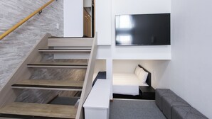 En modern inredning med en trappa, en platt-TV, en soffa och en säng.