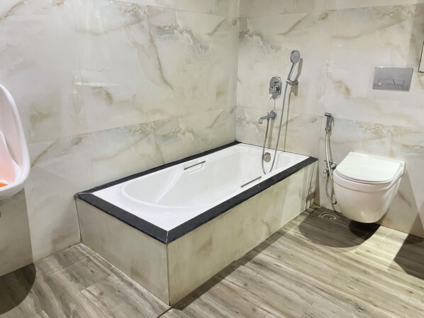 A bathroom with a white bathtub, a toilet, and a shower.