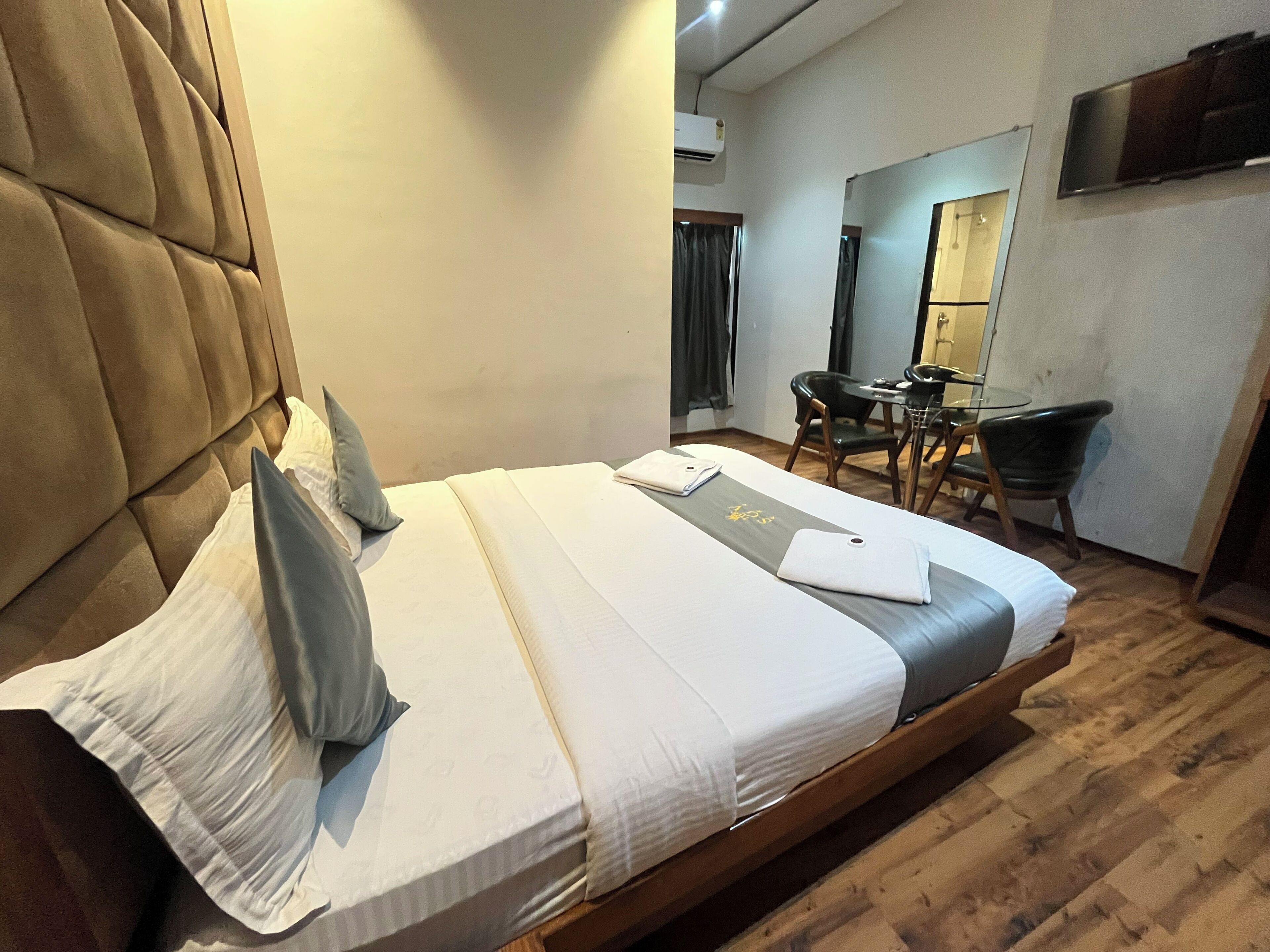 A hotel room with a large bed, a desk, and a chair.