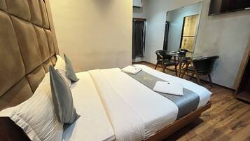 A hotel room with a large bed, a desk, and a chair.