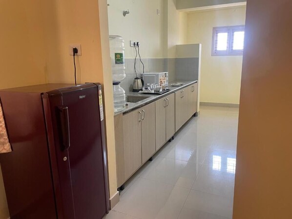 A kitchen with a refrigerator, a water dispenser, and a coffee maker.