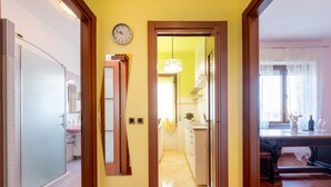 A hallway leading to a kitchen with a clock, a door, and a dining area with a table and chairs. - Cosy apartment of 34 sqm, for 2 people, on the fourth floor of a building with lift (with some steps to access it).The property is located in a lively district and well served by public transport; the apartment is 50 m from the Hospital of Parma and a fe (Parma)