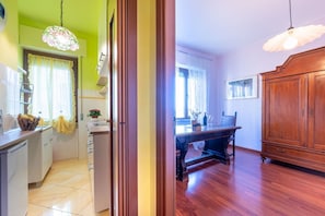 Une cuisine avec un coin repas, des meubles de rangement en bois et un luminaire suspendu.
