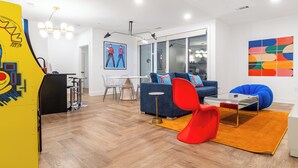 A modern living room with a blue sofa, red chair, and a glass coffee table.