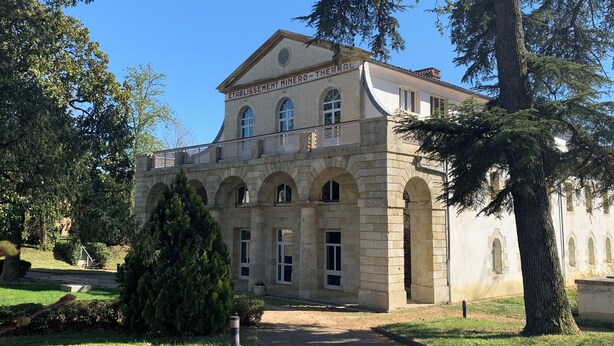 A historic stone building with arched windows and a central entrance, surrounded by well-maintained lawns and trees. - Appartement hotel (Castera-Verduzan)