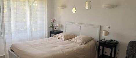 A neatly arranged bedroom with a bed, bedside tables, a lamp, and a chair.