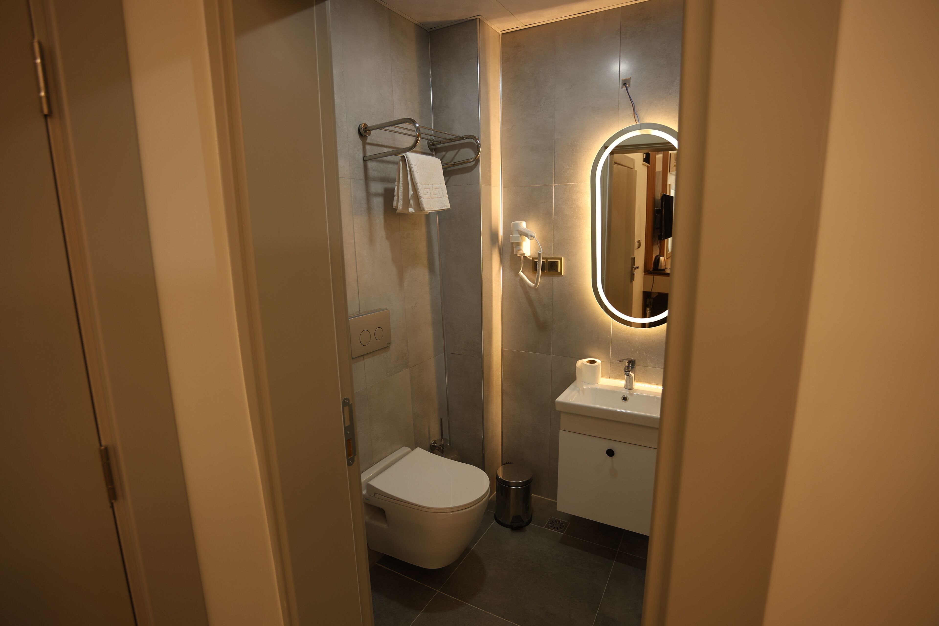 A modern bathroom with a toilet, sink, and mirror.