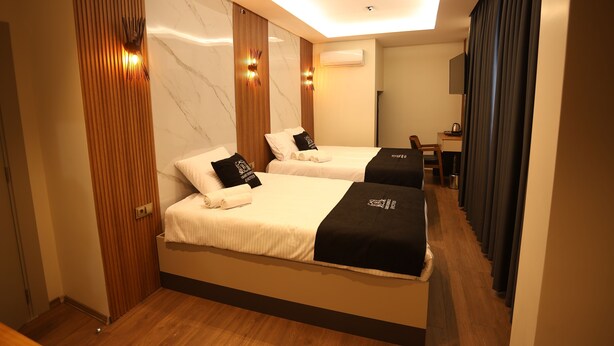 A hotel room with two beds, wooden paneling, marble walls, and a desk with a chair. - Grand Begonville Erciyes Hotel (Develi)