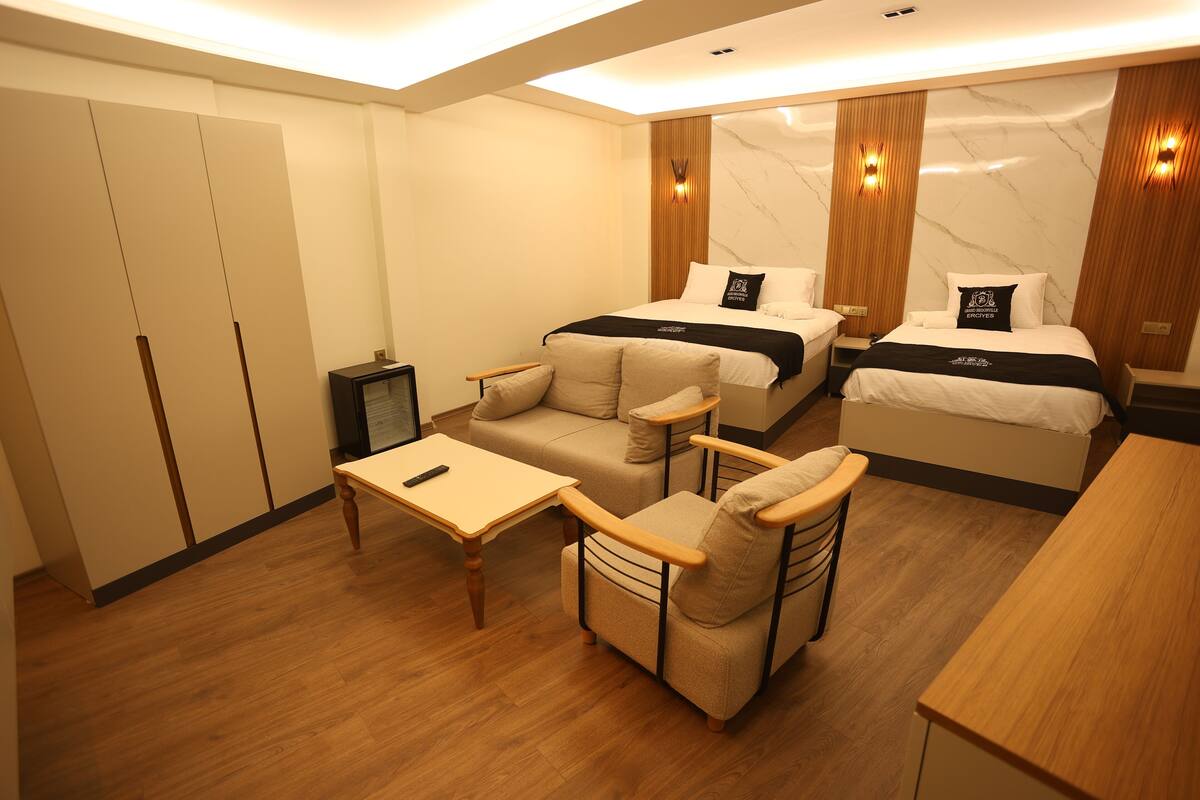 Quarto de hotel com cama, sofá, mesinha e guarda-roupa.