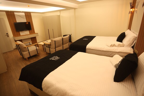 Una habitación de hotel con dos camas, un escritorio, una silla, un televisor y un armario.