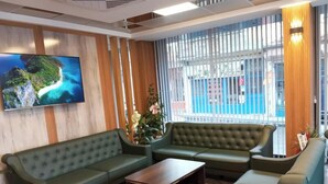 A modern lobby with a green sofa set, a wooden coffee table, and a large TV on the wall. - Grand Begonville Erciyes Hotel (Develi)