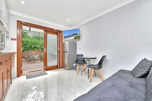 A compact living space with a kitchenette, a dining area, and a seating area with a sofa and chairs.