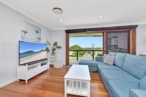 A living room with a television, sofa, coffee table, and a view of the outdoors through a sliding glass door.