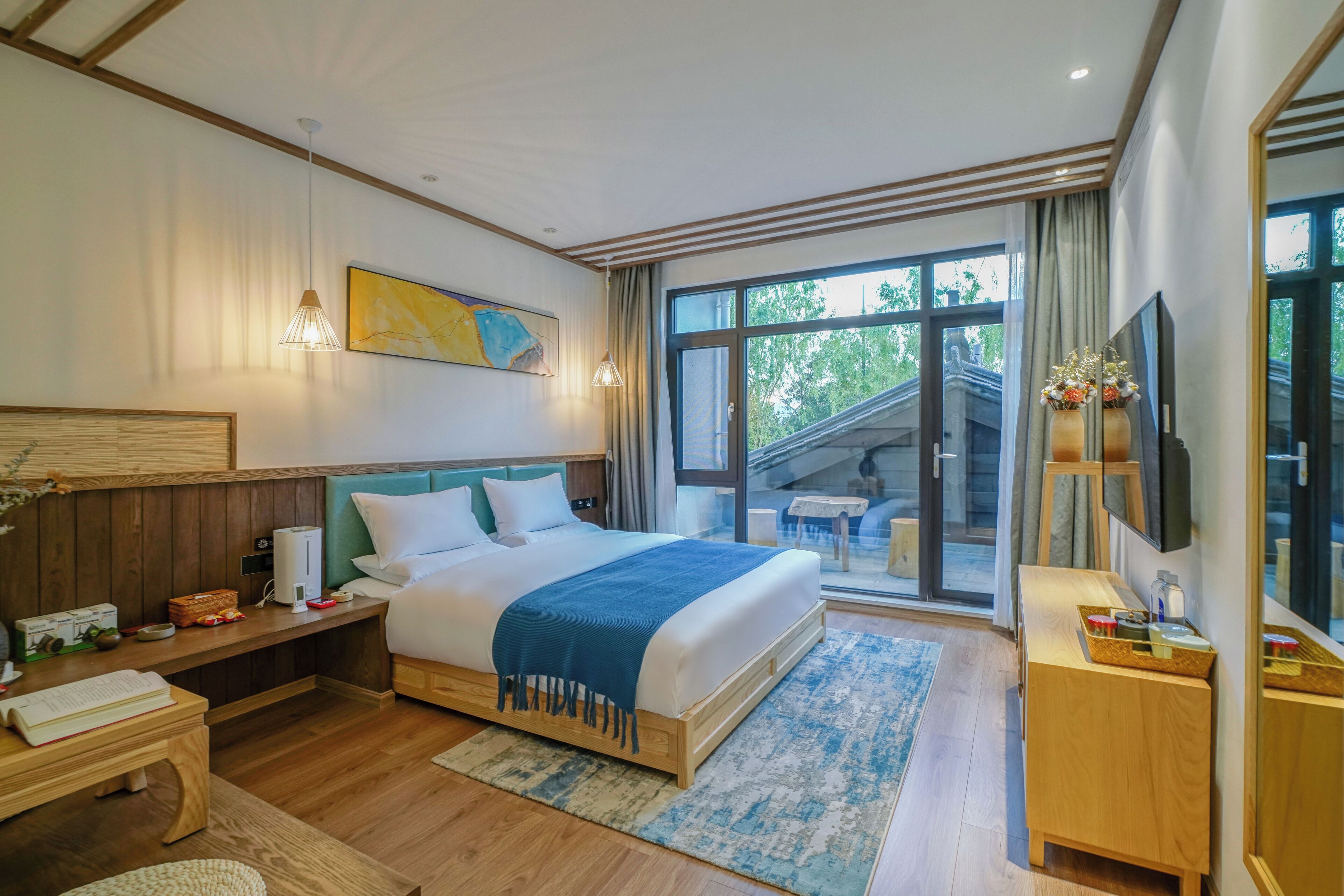A modern hotel room with a large bed, a desk, a TV, and a view of the outdoors.