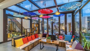 A modern interior with a glass ceiling, seating area, and decorative umbrellas. - Lijiang Xisu Garden (Lijiang)