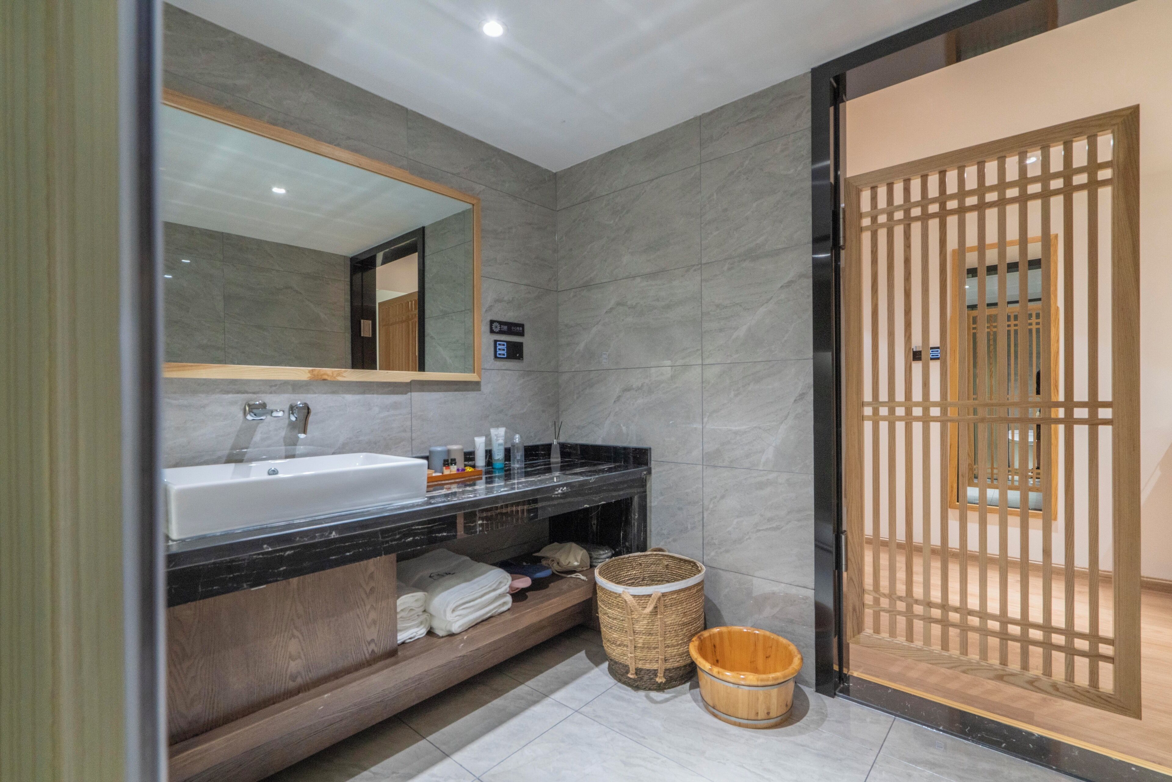 A modern bathroom with a large mirror, a sink, and a wooden vanity.