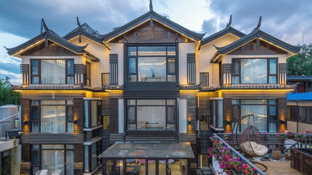 A modern multi-story house with large windows, a balcony with seating, and a glass-enclosed porch area. - Lijiang Xisu Garden (Lijiang)