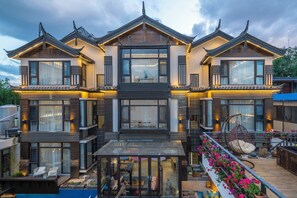 Ein modernes Mehrfamilienhaus mit großen Fenstern, einem Balkon mit Sitzgelegenheit und einem überdachten Glasbalkon.