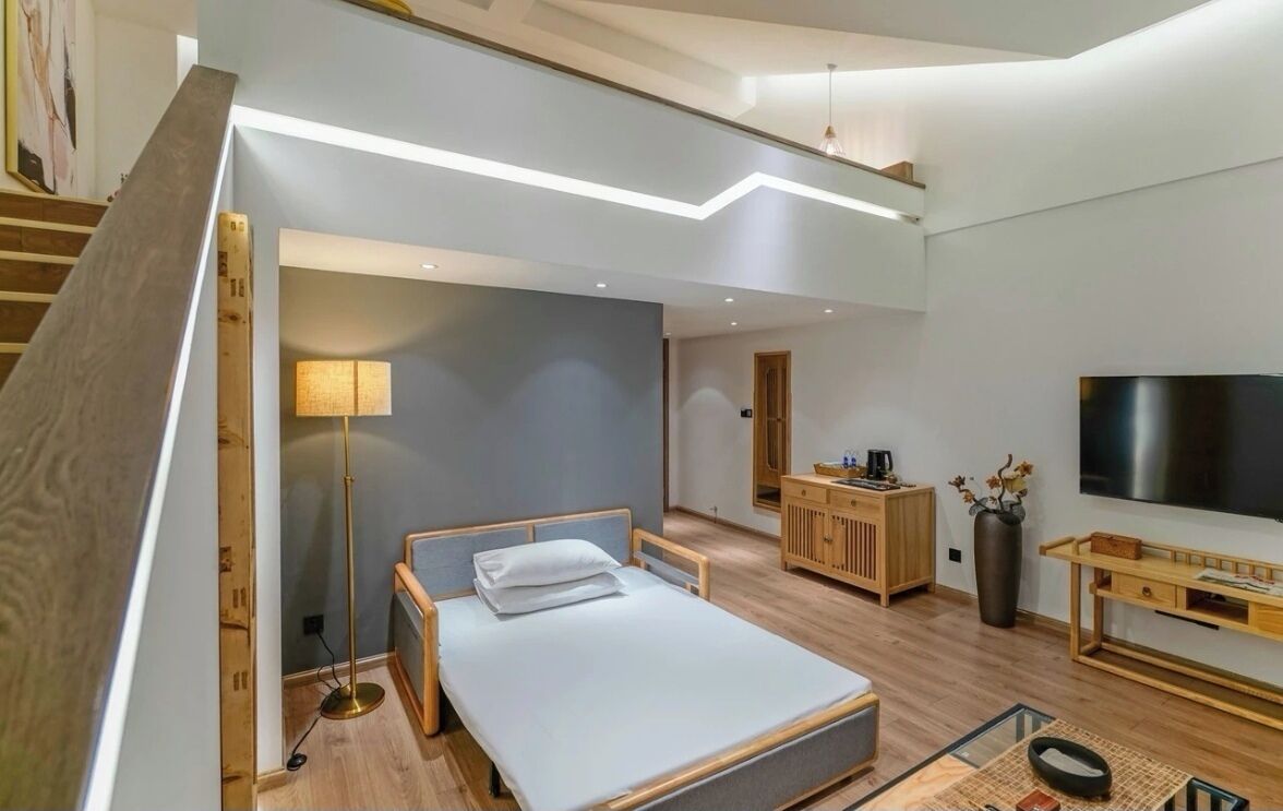 Une chambre moderne avec un lit, une table de chevet, une lampe et un grand téléviseur.