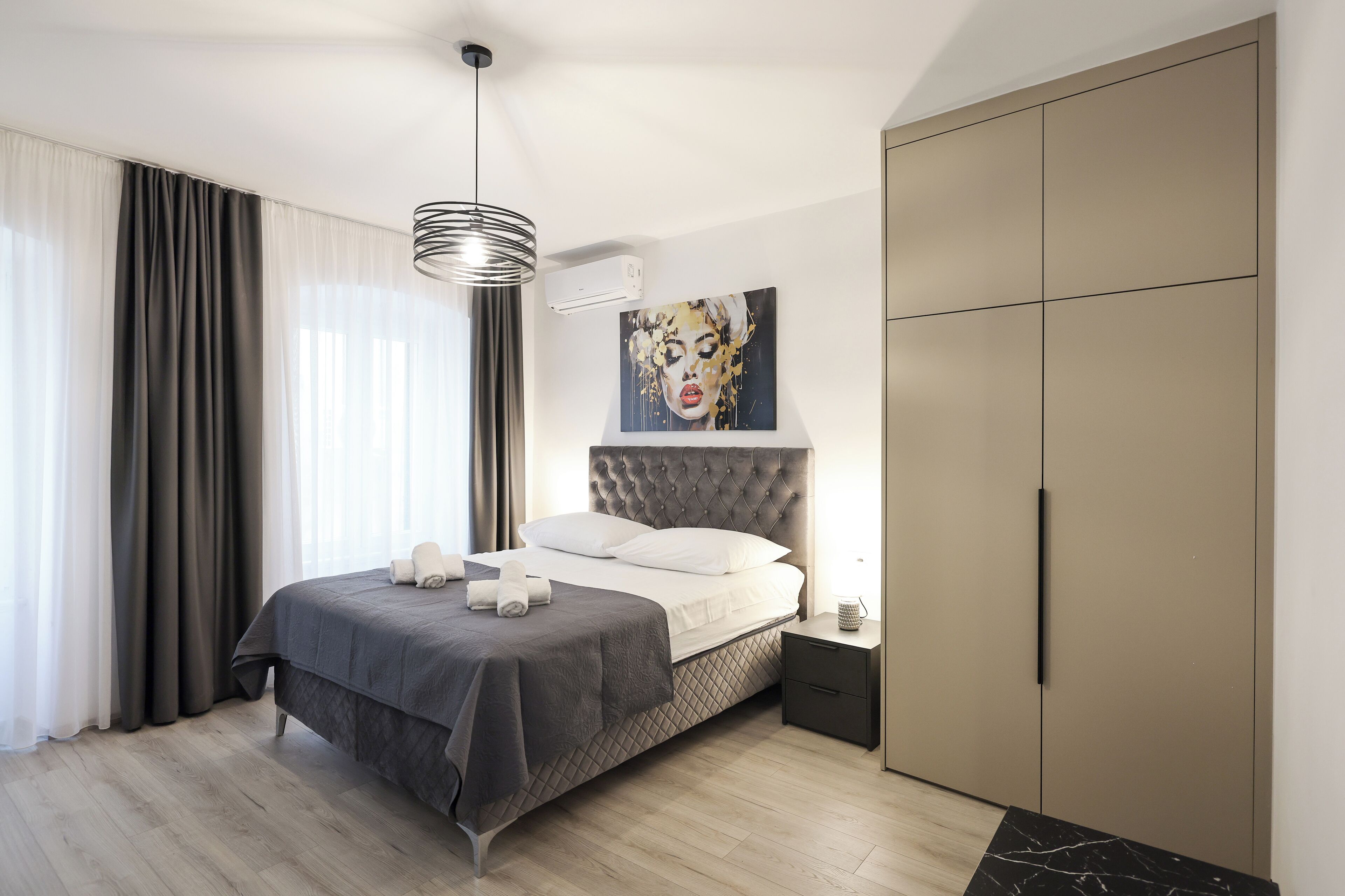 Een moderne slaapkamer met een groot bed, een garderobe en een schilderij aan de muur.