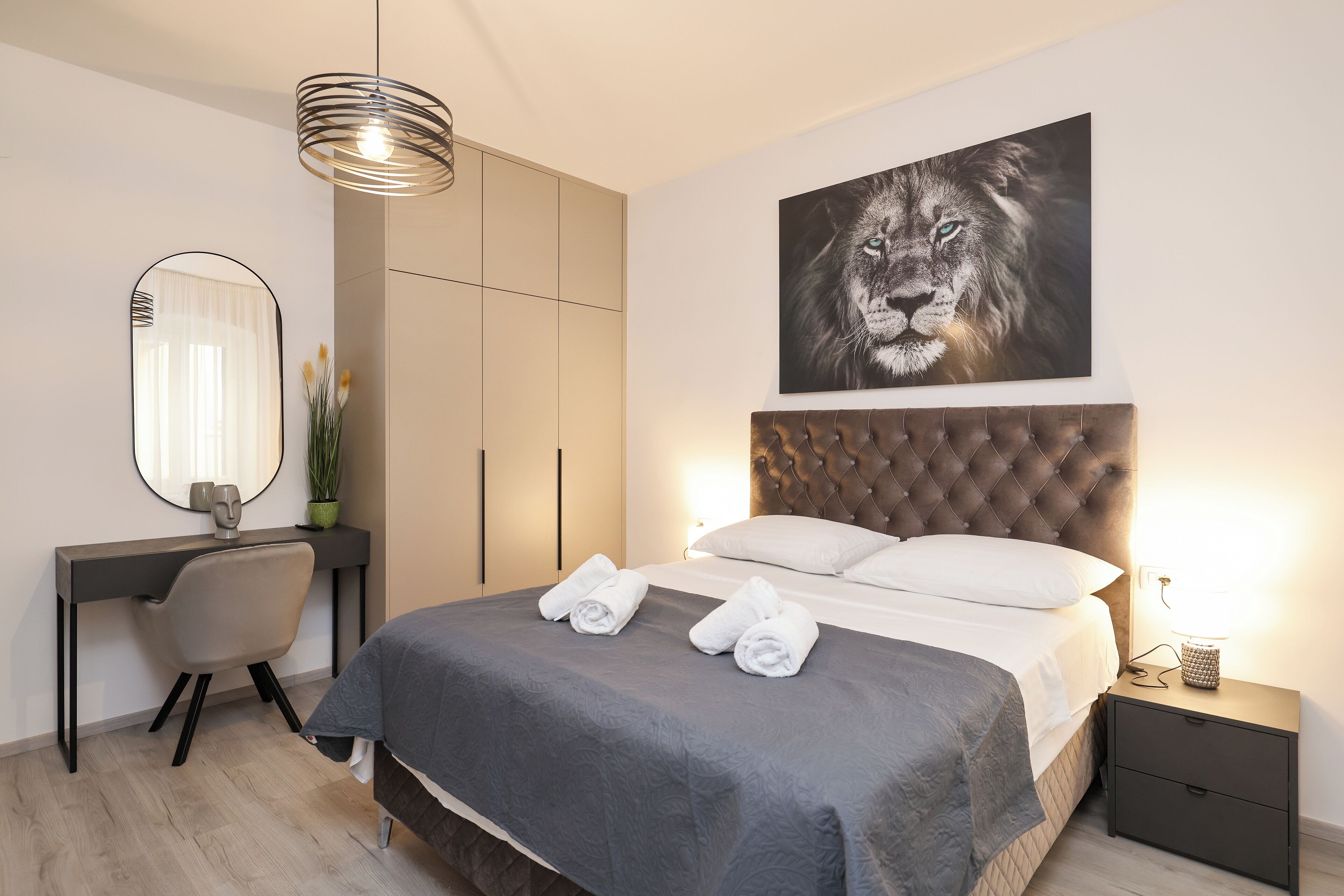 Un dormitorio moderno con una cama grande, un escritorio, una silla y una obra de arte en la pared de un león.