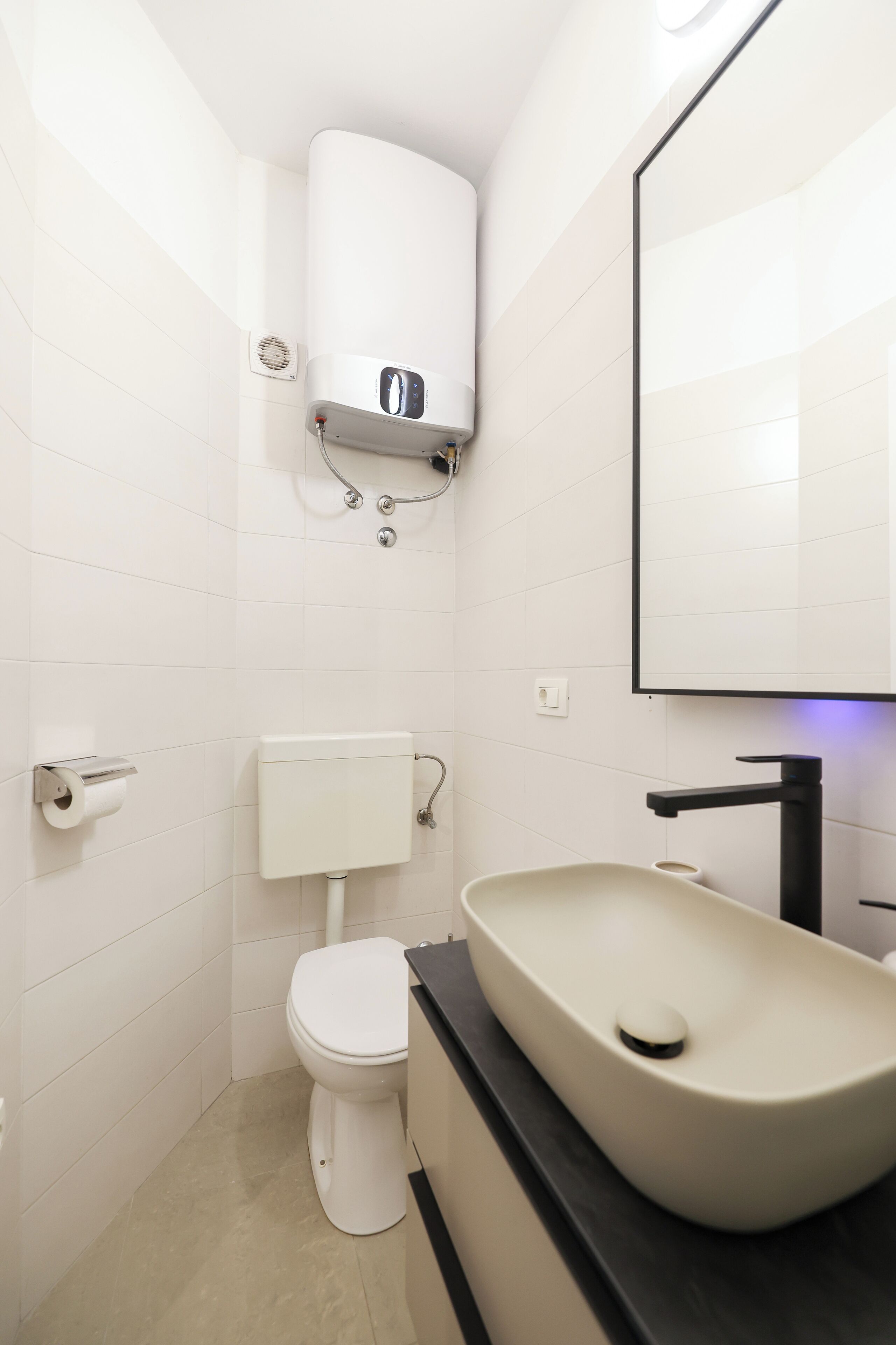 A modern bathroom with a toilet, a sink, and a mirror.