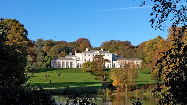 Ein großes, weißes Gebäude mit vielen Fenstern und einer Grünfläche davor.