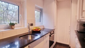 Eine moderne Küche mit weißen Schränken, einer schwarzen Arbeitsplatte, einem Spülbecken und einem Fenster mit Blick auf Bäume.