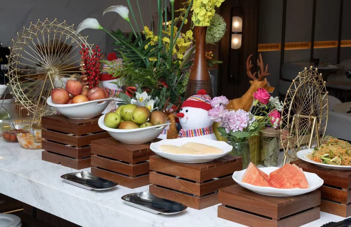 A buffet table with various food items, including fruits, vegetables, and a decorative snowman figure.