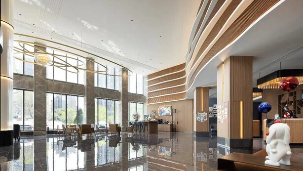 Un vestíbulo amplio con techos altos, ventanas grandes y una zona de recepción de diseño moderno.