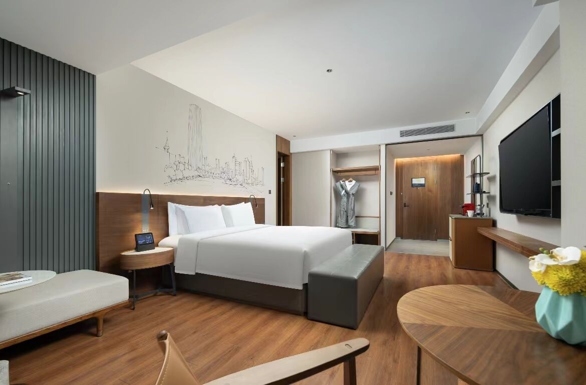 Una habitación de hotel moderna con una cama grande, un escritorio, una zona de estar y un televisor.