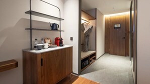Un baño moderno con tocador de madera, repisas con artículos de aseo personal y zona de ducha con puerta de vidrio.