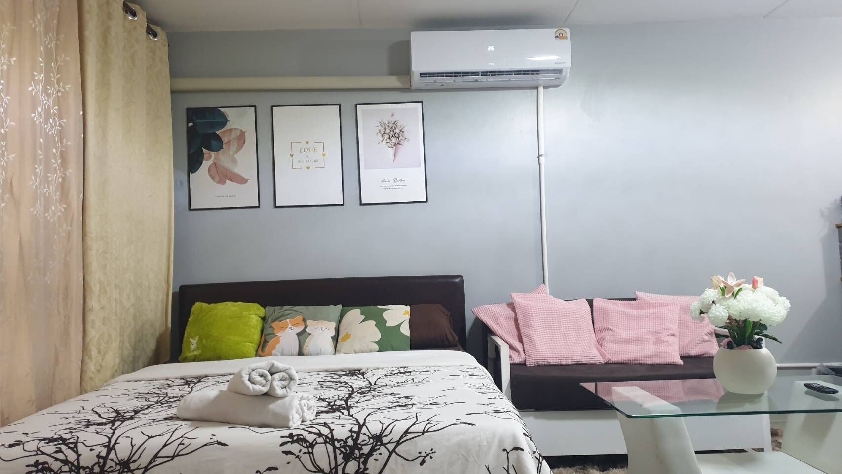 Una camera da letto con un letto, un divano, un tavolino in vetro e un condizionatore d'aria a parete.