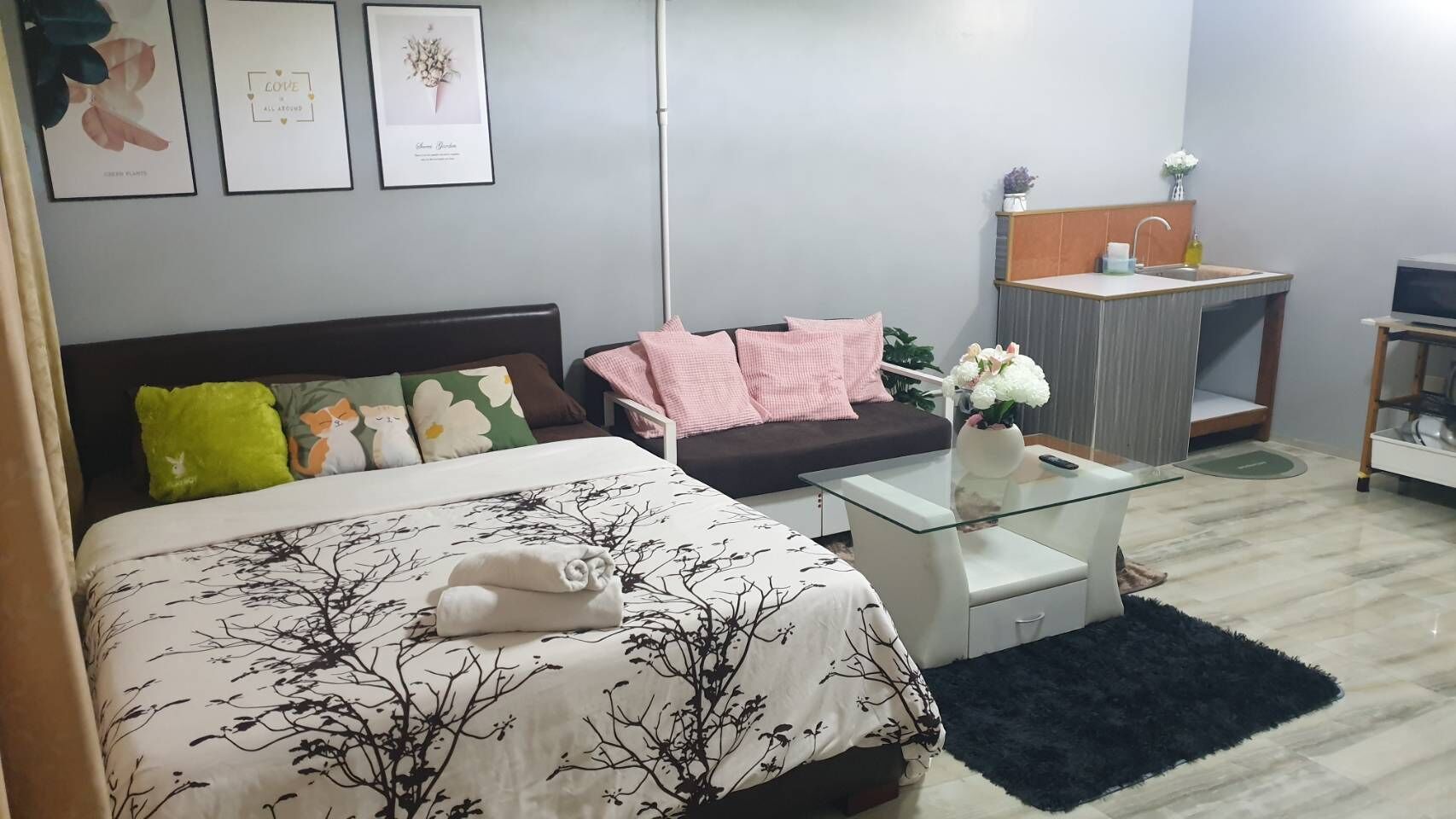 Una camera da letto con un letto, un divano, un tavolino in vetro, un piccolo comodino e una TV a parete.