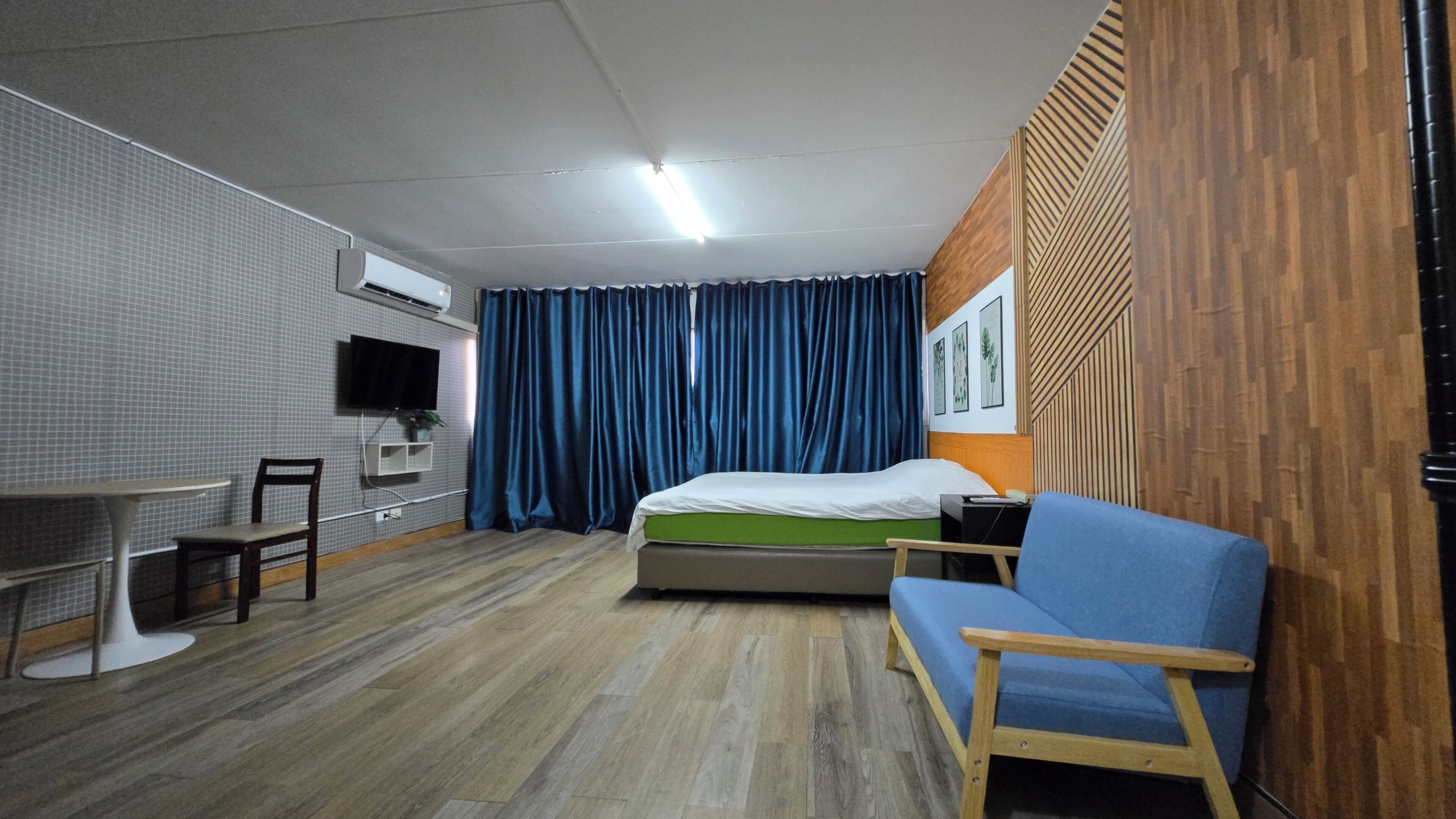 Ett hotellrum med en säng, ett skrivbord, en stol, en tv och ett fönster med gardiner.