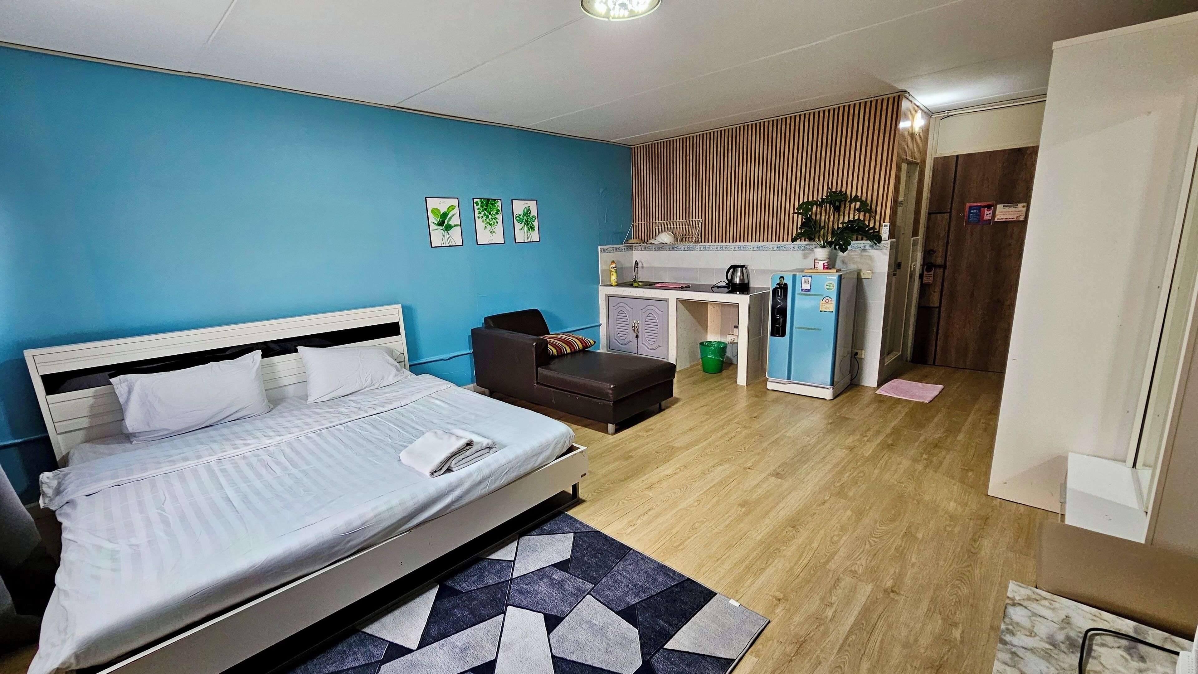 A compact room with a bed, a desk, and a kitchenette.