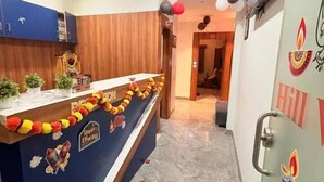 Un área de recepción con mostrador, paneles de madera, ventilador de techo y una pared con adornos festivos.
