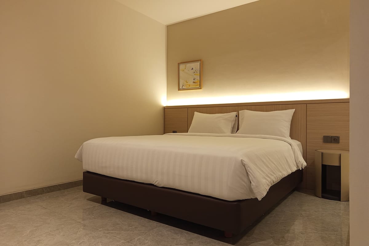 Ein modernes Hotelzimmer mit einem großen Bett, einem Nachttisch und einer Wandleuchte.