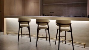 Een moderne keuken met houten kastjes, een centraal eiland met krukken en uitzicht op de stad.