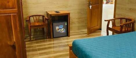 Ein Zimmer mit einem Bett, zwei Holzstühlen, einem kleinen Tisch mit Fernseher und einem Kleiderschrank.
