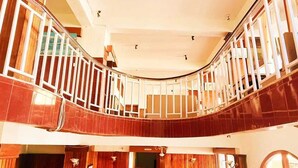 A curved staircase with wooden railings and a view of the lower level. - HOTEL TASHI GYAL TSEN (Gyalshing)