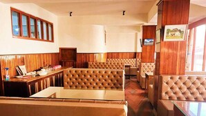 A restaurant with booth seating, wooden paneling, and a counter with a menu. - HOTEL TASHI GYAL TSEN (Gyalshing)
