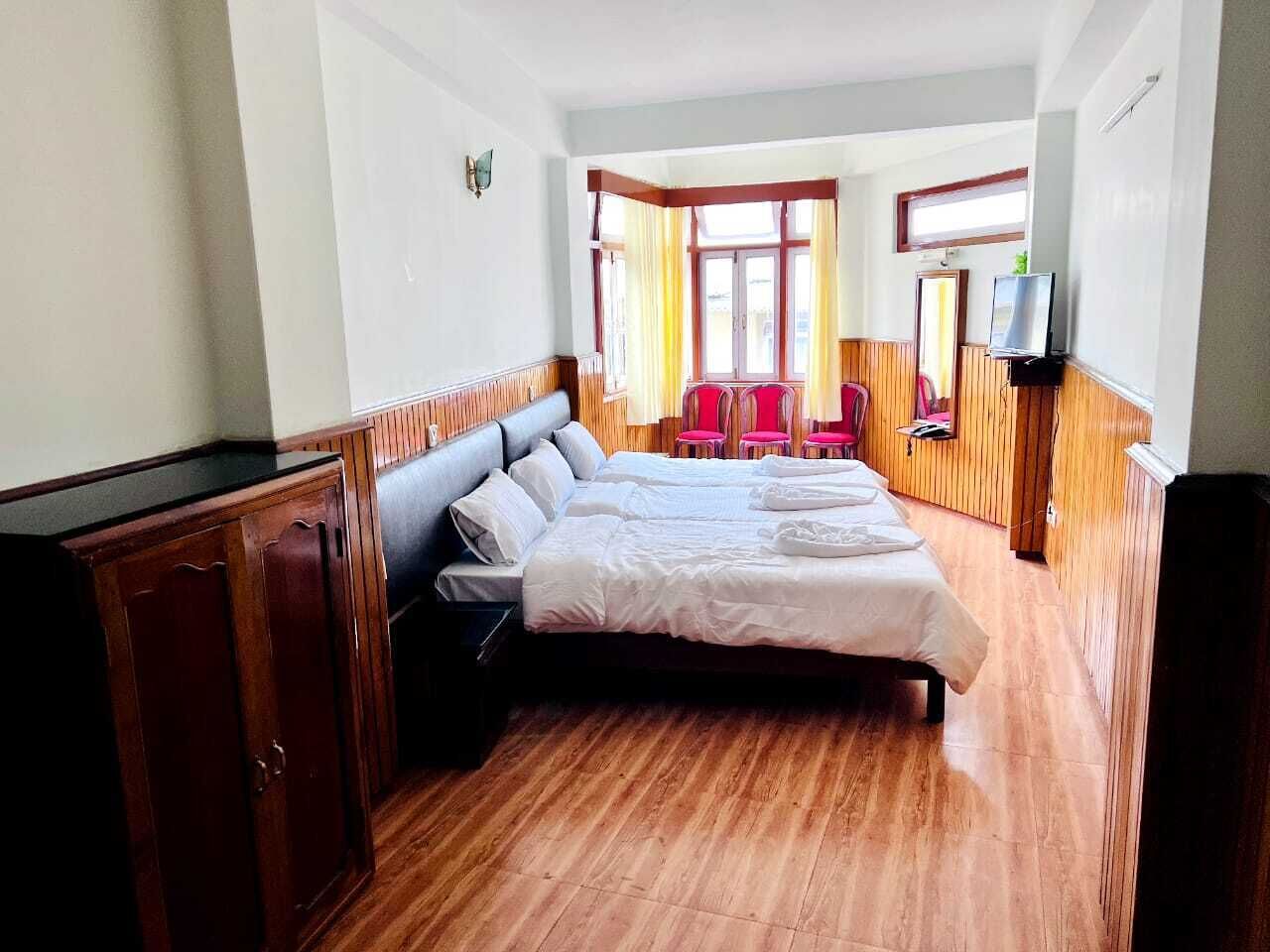 A hotel room with a large bed, wooden flooring, a desk with a chair, and a television.