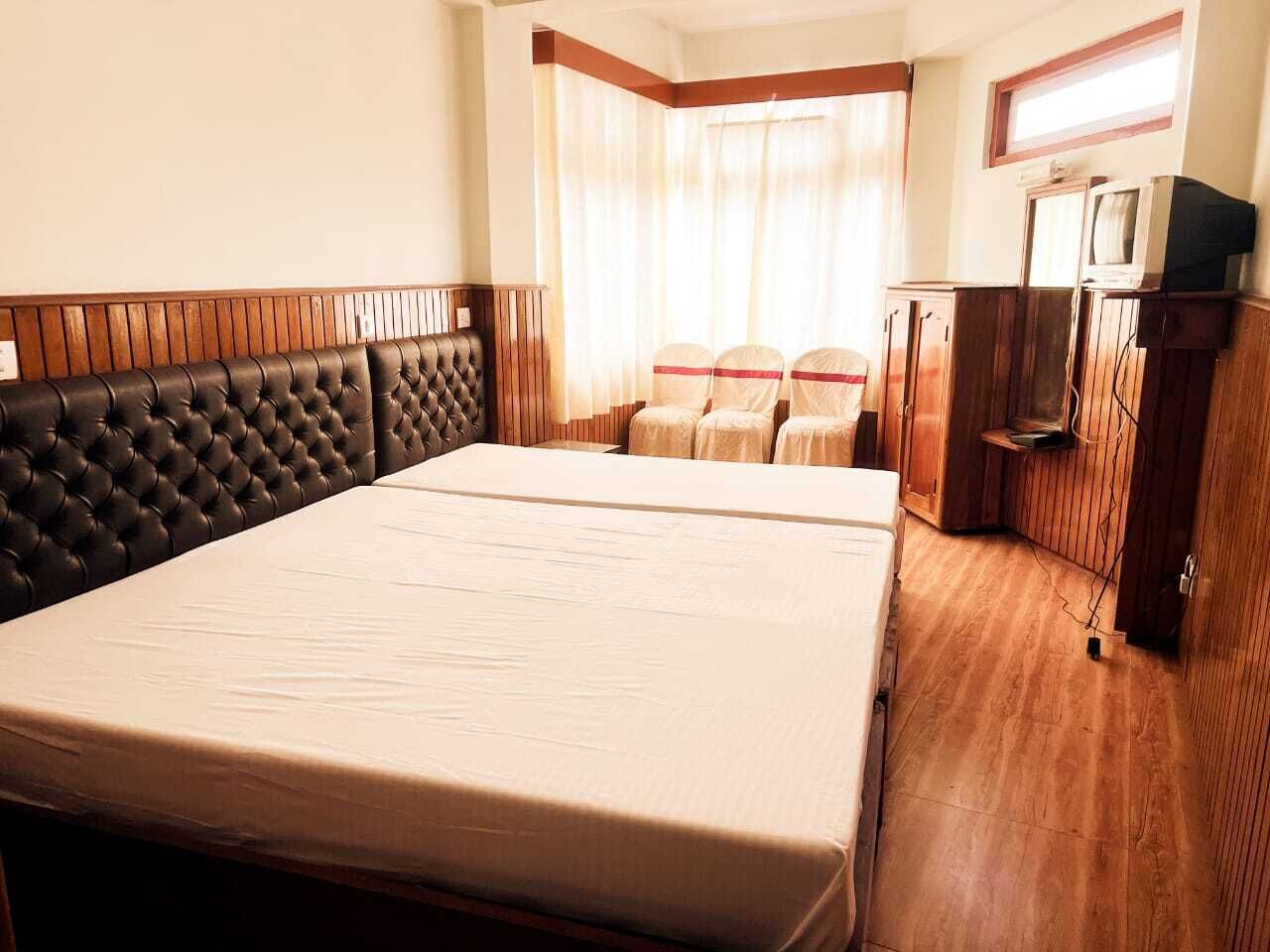 Une chambre d’hôtel avec un grand lit, des boiseries, un petit bureau et un téléviseur.