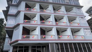 A multi-story hotel with balconies, a red awning, and a sign for 'HOTEL TASHI GYAL TSEN'. - HOTEL TASHI GYAL TSEN (Gyalshing)